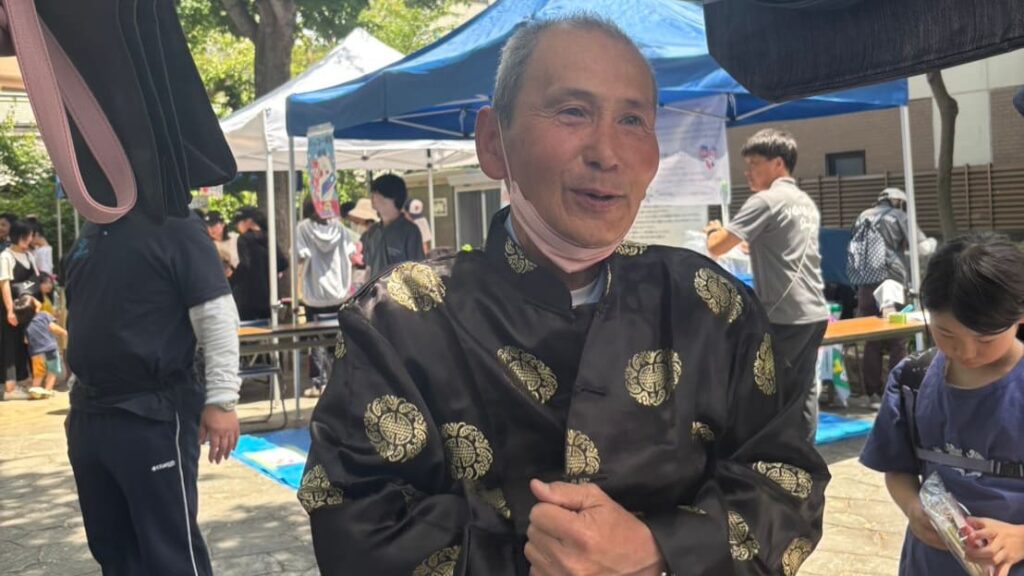 十三こどもキラキラまつりのバザーで購入したチャイナ服を試着する警備員のおっちゃん