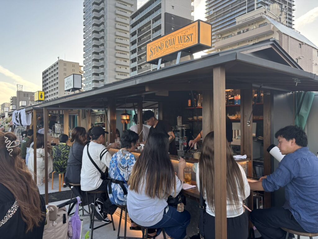 淀川つつみ市ミナモ十三のSTAND RAW WESTで食事を楽しむ来店客